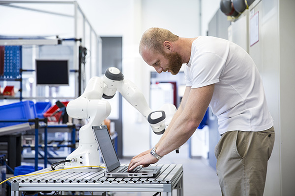 industry 4.0: Young engineer works at a robotic arm